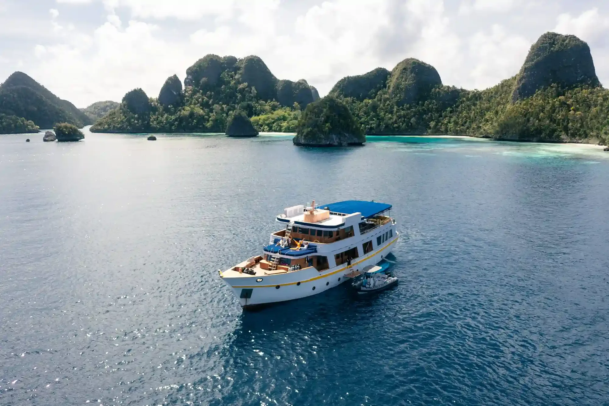 A phinisi liveaboard under sail in golden evening light