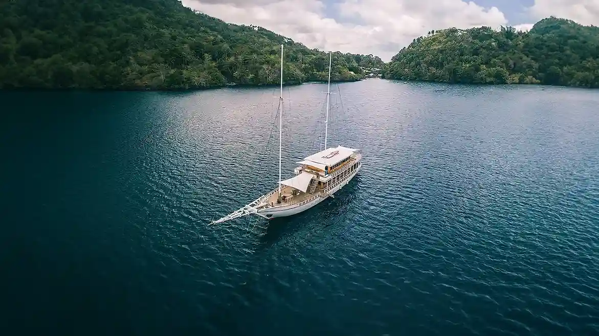 A yacht at anchor in a sheltered bay at first light